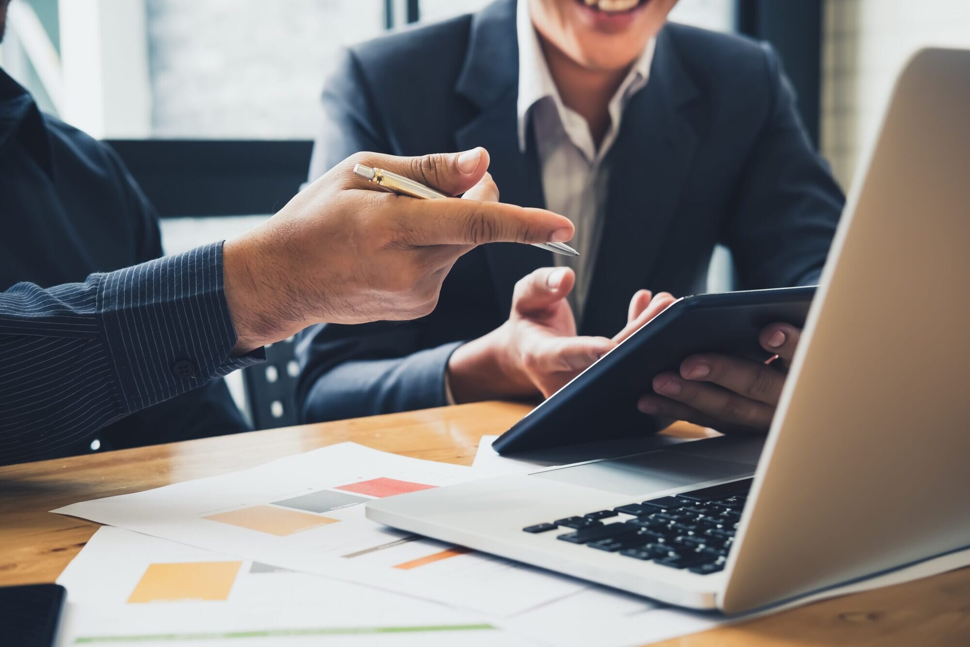 People by a desk with a laptop talking